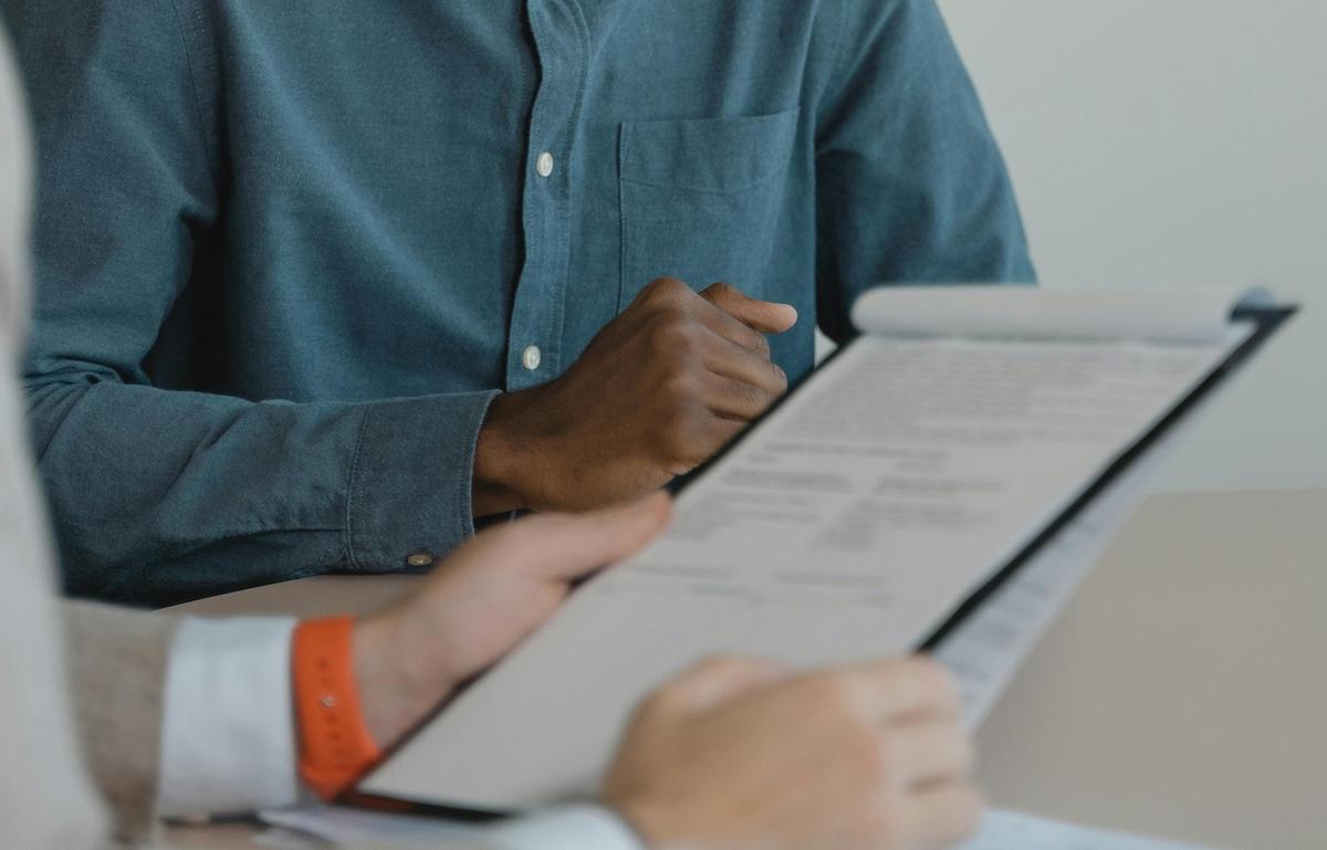 a closeup of two people's hands, one pair holding a notepad