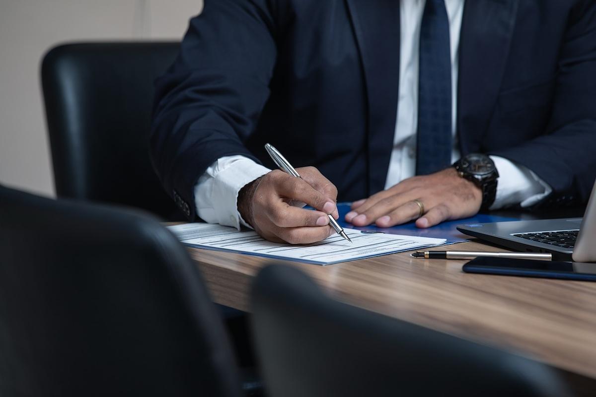 a closeup of a person's hands signing a document